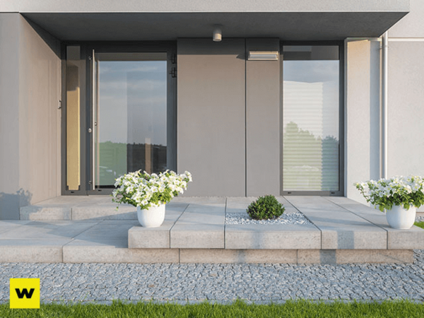 Moderner Hauseingang mit großen Glasfronten, Pflanzkübeln und gepflegtem Eingangsbereich.