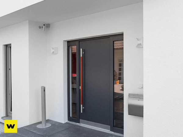 Moderne Haustür aus Aluminium mit Seitenteil und Edelstahlgriff an weißer Hausfassade.
